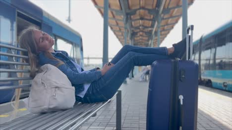 train ride. a female tourist with a suitcase rests at the railway station and waits for the arrival of the train