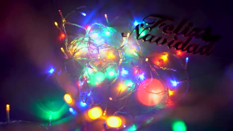 beautiful colored led lights draw cycles on the image while a hand places and removes a sign in which you can read merry christmas in spanish