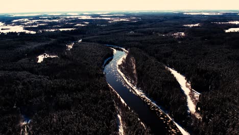 Un-Río-Sinuoso-Cerca-De-Un-Pequeño-Pueblo-Con-Un-Macizo-Forestal