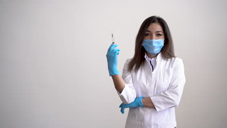 female doctor wearing medical mask holding a syringe with a vaccine for covid 19