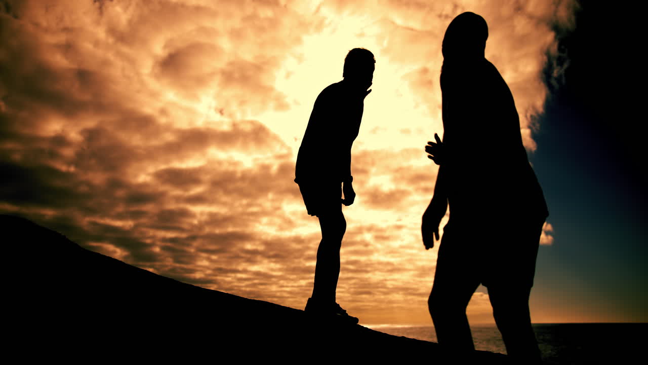 Silhouettes of people celebrating success against a dramatic sunset