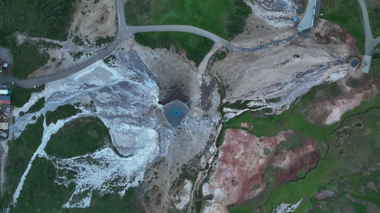 아이슬란드의 게이시르 지열 지역의 드론 촬영, 생생한 파란색 온천, 다채로운 지형 및 경로를 강조합니다.