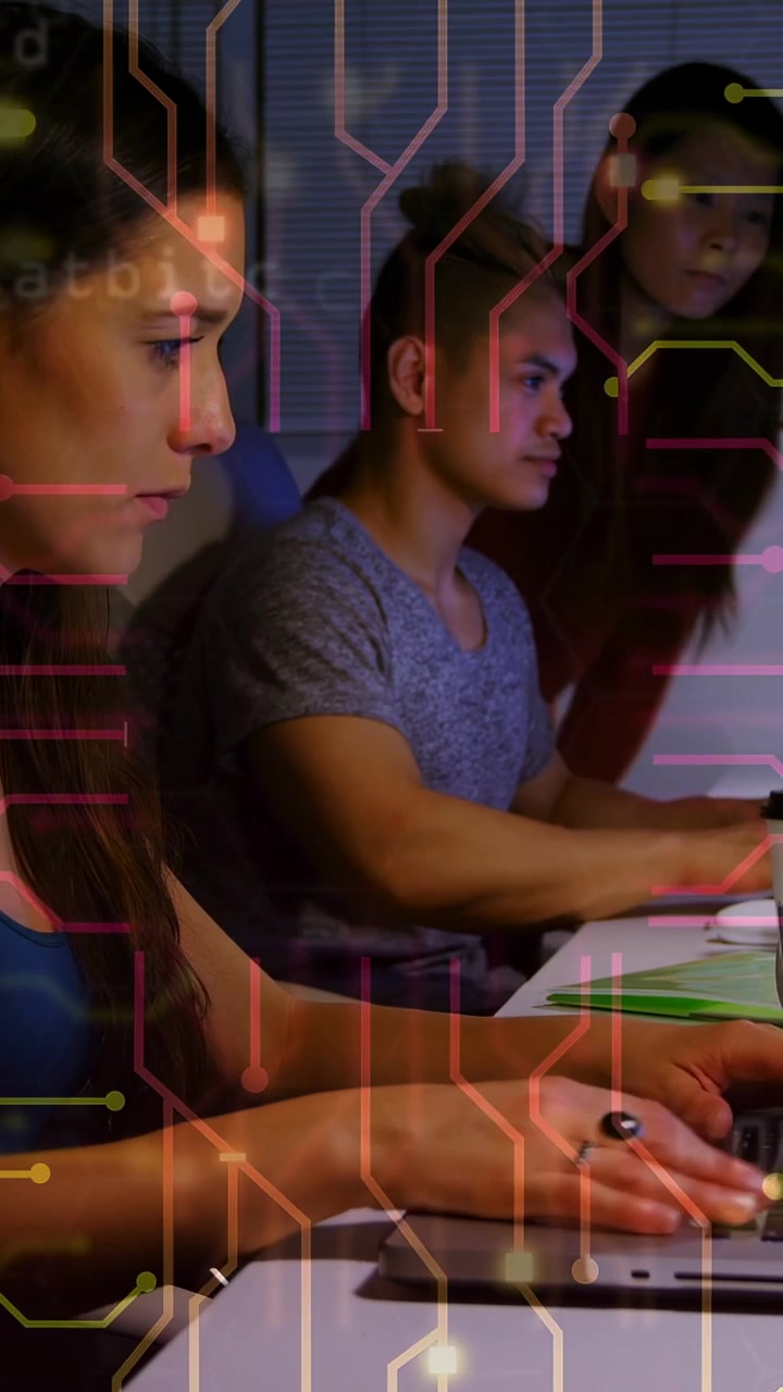 Vertical video: Left woman typing as camera pulling back, circuit overlay tracing keys on tech work