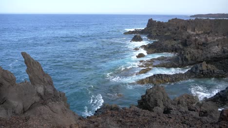 waves crashing on the coast of volcanic black rocks on the island of lanzarote