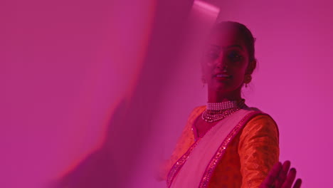 fotografía de estudio con reflejos de una bailarina de kathak que realiza un baile vestida con el vestido tradicional indio contra un fondo púrpura 1