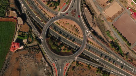 aerial: roundabout with cars and traffic during the day in gran canaria, spain, spiral top down drone shot