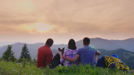 一对带着狗的游客欣赏着山上的美丽风景,他们坐在地上