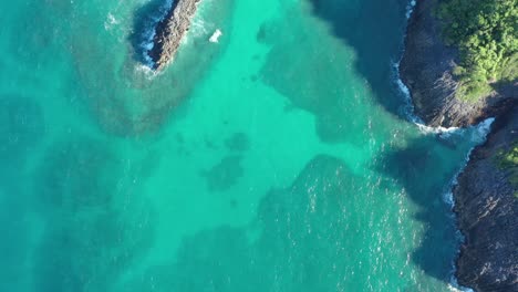 aerial top-down view of waves breaking on coast of hermitano beach in dominican republic