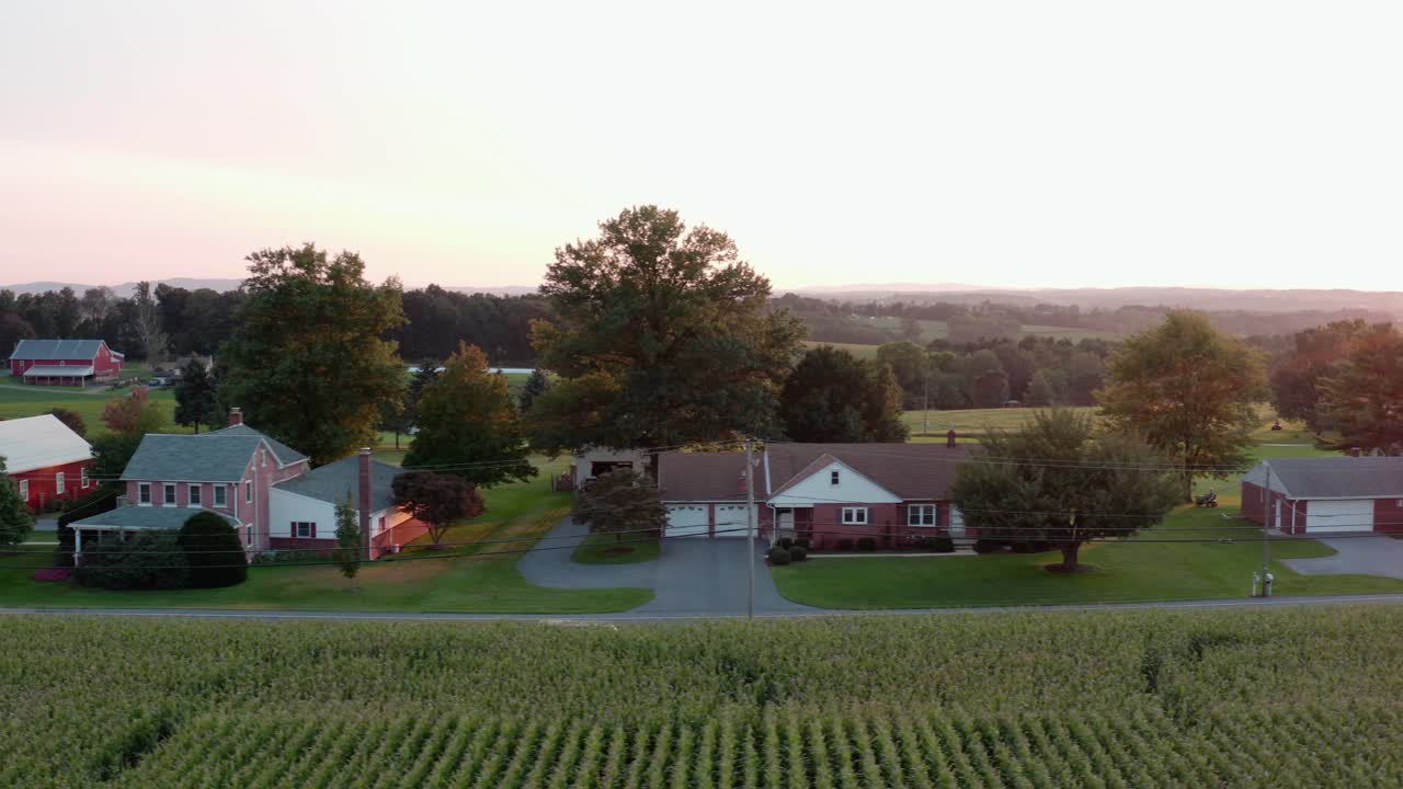 Aerial establishing shot of rancher homes in rural America during summer sunset, golden hour light