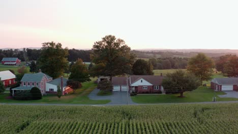 aerial establishing shot of rancher homes in rural america during summer sunset, golden hour light