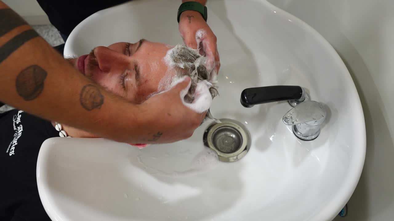 Playful scene of hairdresser applying shampoo and placing a foam spot on customer's nose creating a funny salon moment