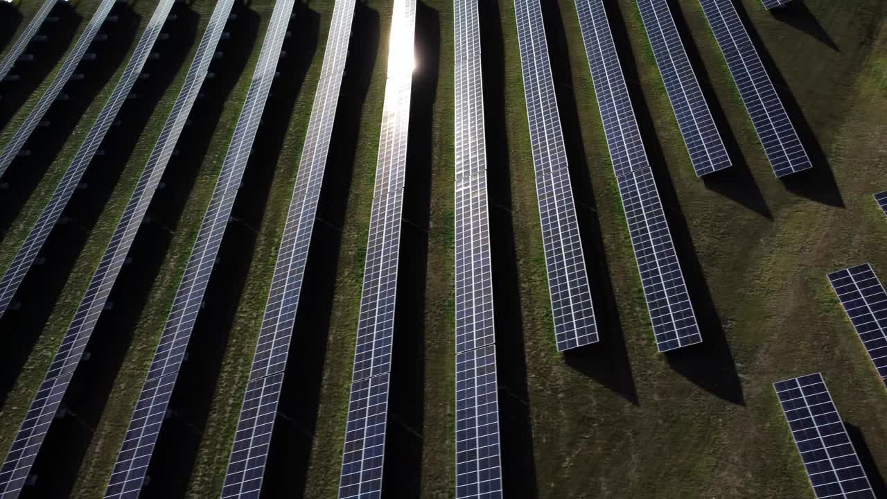 Droneoptagelse fra siden af solcellefeltet, der reflekterer solens stråler.