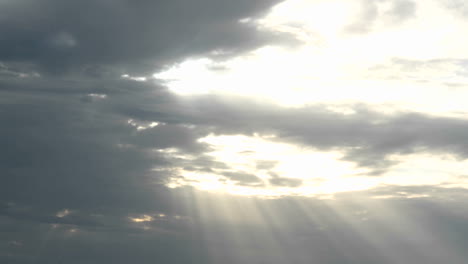 Sonnenstrahlen-Scheinen-Durch,-Während-Eine-Helle-Goldene-Sonne-Hinter-Dunklen-Wolken-Verschwindet