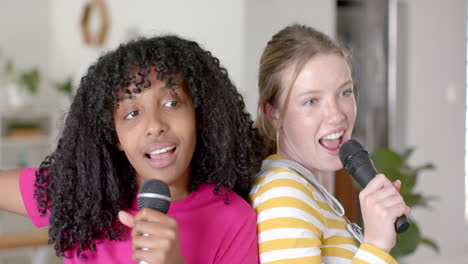 happy diverse teenage female friends dancing and singing at home, slow motion