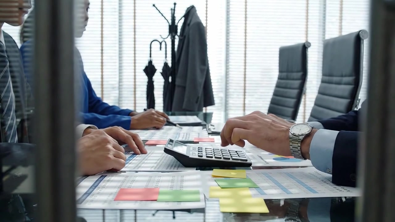 Engaged in Calculations: Business Professionals Collaborate at a Boardroom Table, Analyzing Data and Making Decisions with Calculators and Notes