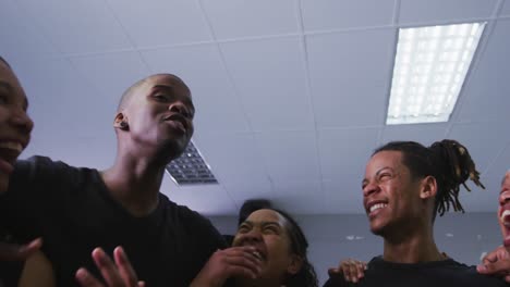 Multi-ethnic-group-of-fit-male-and-female-modern-dancers-standing-in-a-huddle-