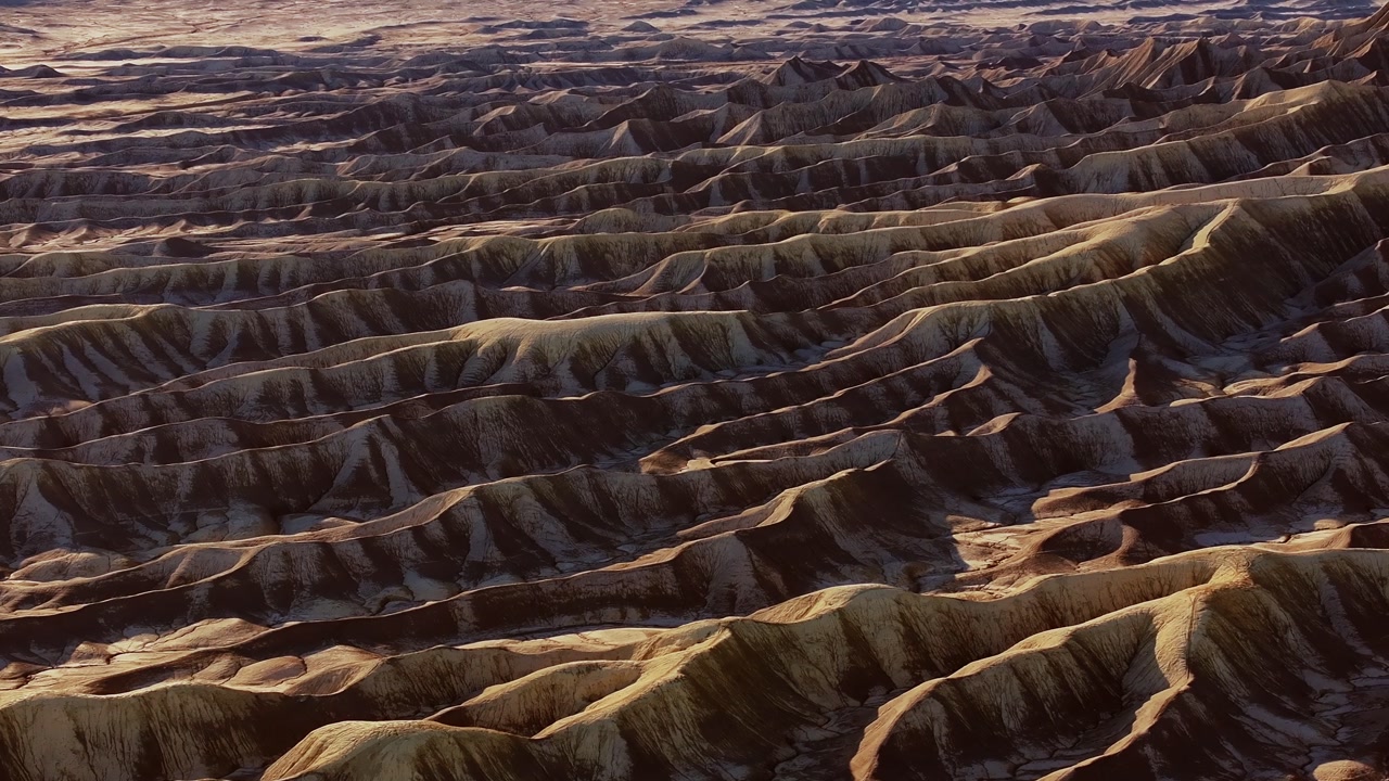Layered desert ridges and eroded badlands textures in arid landscape, moon or mars aerial background