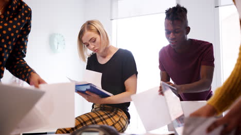 Young-creative-business-team-discussing-paperwork-together-in-a-meeting-room,-low-angle