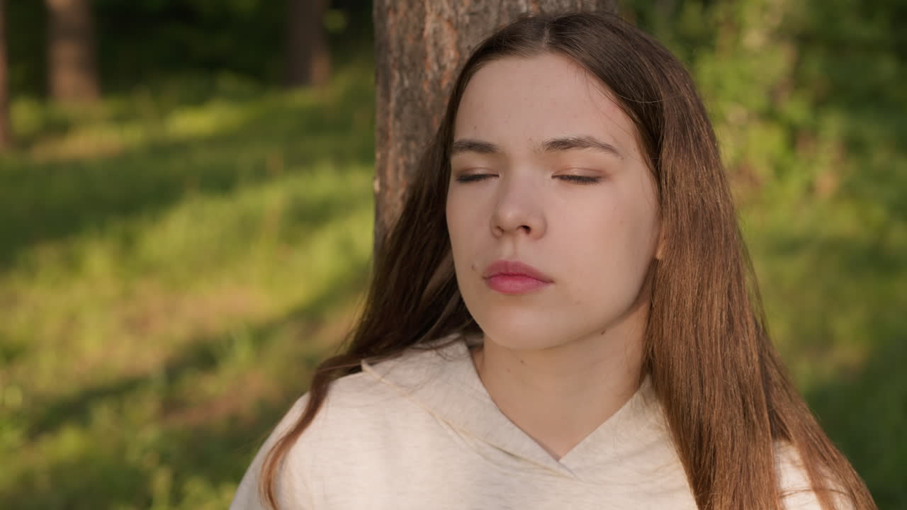 나무 줄기에 기대어 누워있는 여인, 얼굴에 사려 깊은 표정을 가진 여성, 삶의 문제와 슬픈 기억에 대해 생각하고, 울창한 숲에서 혼자 억압.