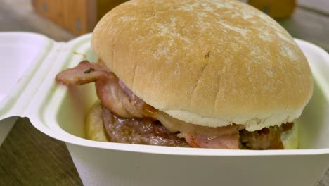 close-up of a greasy fast food burger in a throwaway box, highlighting the unhealthy, quick meal option