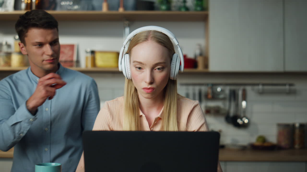 Business woman working home on laptop with headset man trying distract closeup