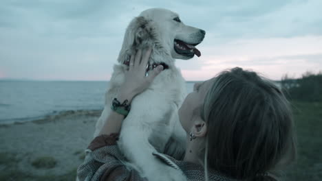 Woman-Petting-Lovely-Golden-Retriever-on-Lakeshore-in-Evening