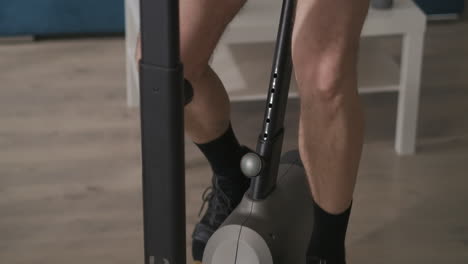 middle aged man on exercise bike at home closeup shot from feet to face during workout healthy lifestyle and sport activities