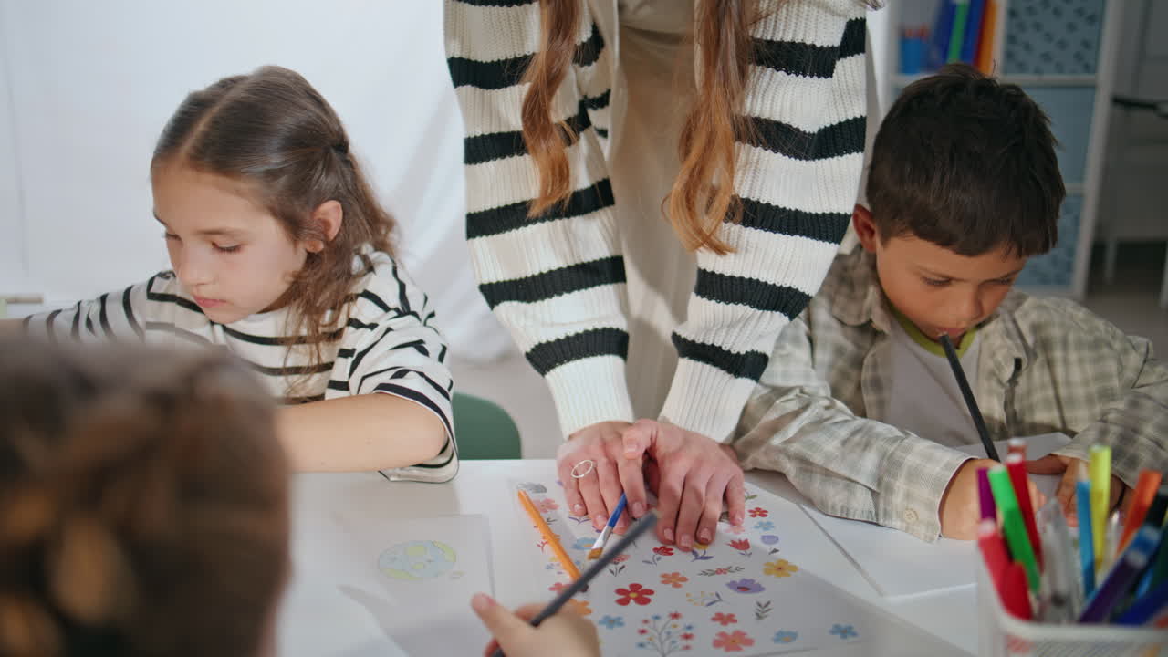 Focused schoolchildren art lesson at school closeup. Woman teacher helping kids