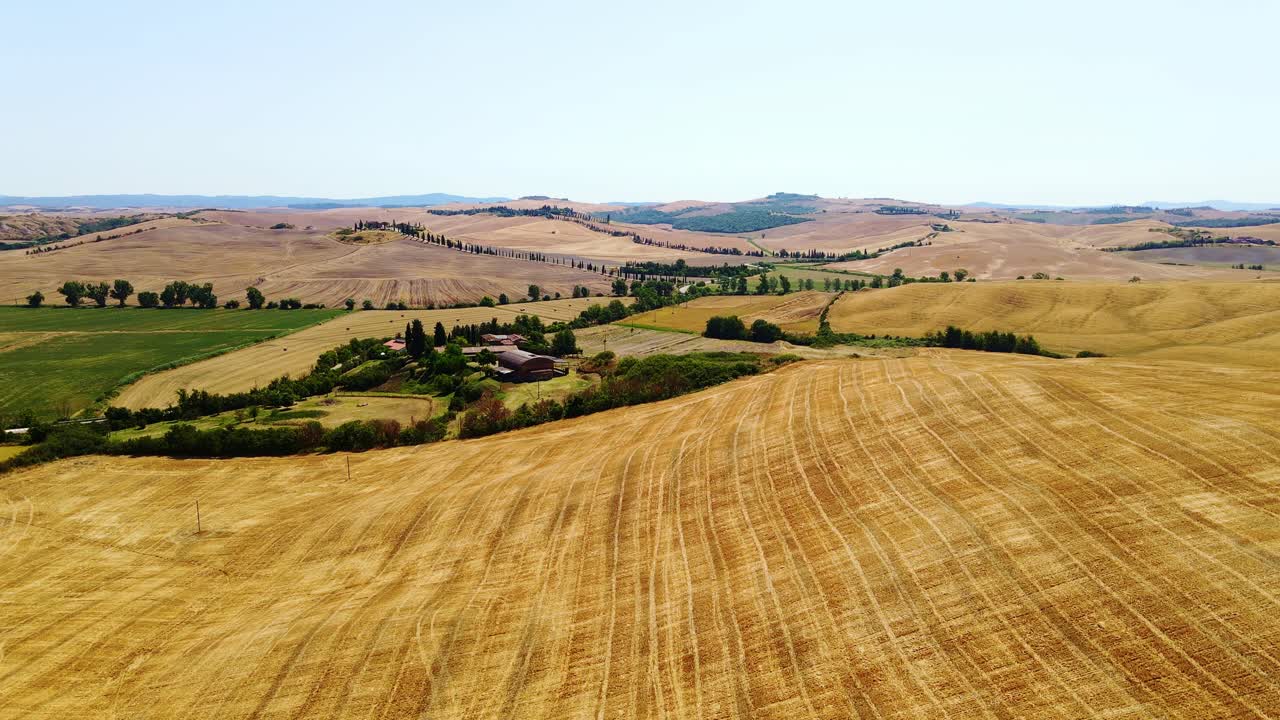 Sweeping view of sun-drenched Tuscan farmland and golden wheat stubble fields