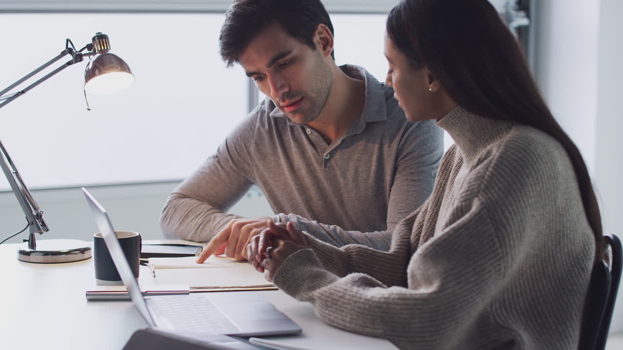 mujer de negocios trabajando en una computadora portátil en un escritorio con un colega masculino usando una tableta digital y un lápiz óptico