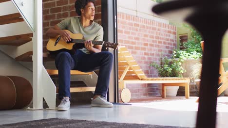 happy african american man plays guitar and singing at home