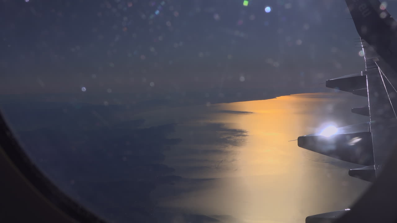 View from an airplane window of the sunset reflecting on the sea