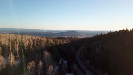 Drone-shot-of-the-sun-setting-over-the-forest-in-Flagstaff,-Arizona