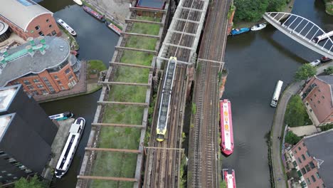 aerial drone flight over castlefield quays with a birdseye view following a tram on a bridge and slowly tilting up to reveal a view of manchester city centre skyscrapers