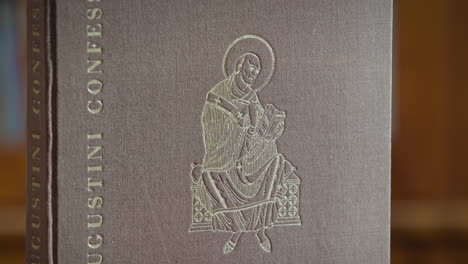 close up of an book cover with the title augustini confessiones, a pisture of st