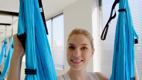 mujer sentada en un columpio de hamaca en el estudio de fitness 4k
