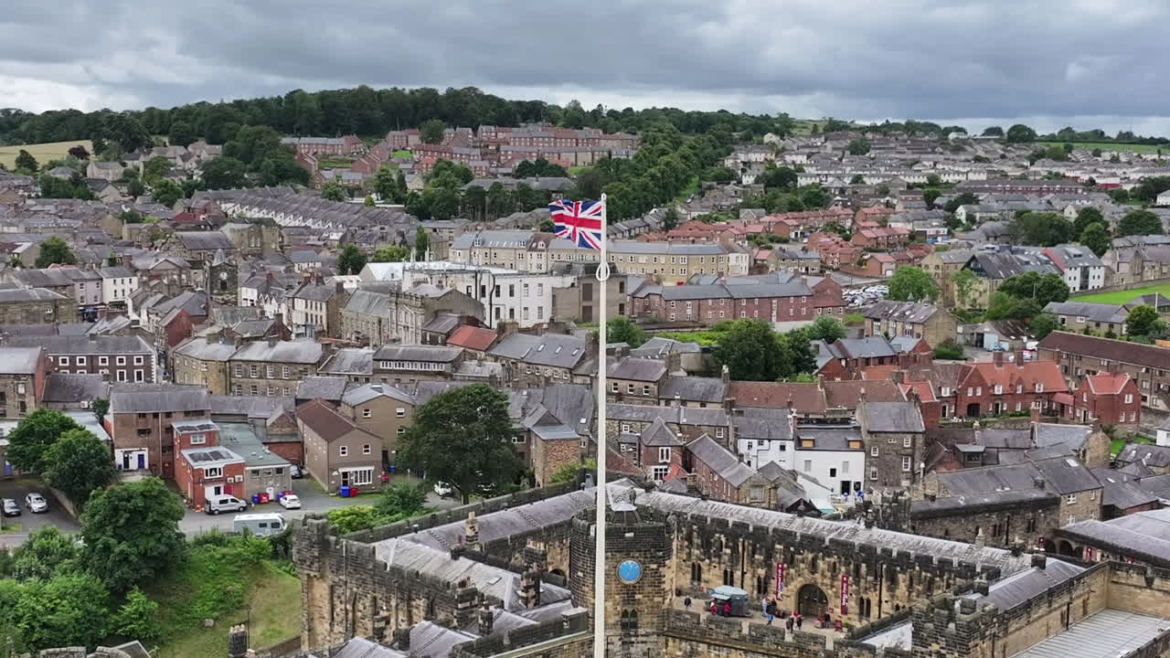 영국 국기가 알누이크 중세 성과 마을 위에 있는 기둥에 흔들리는 공중 사진.