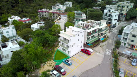 ariel drone orbit shot over sai kung hong kong village house. revealing private traditional housing estates and woods roads.