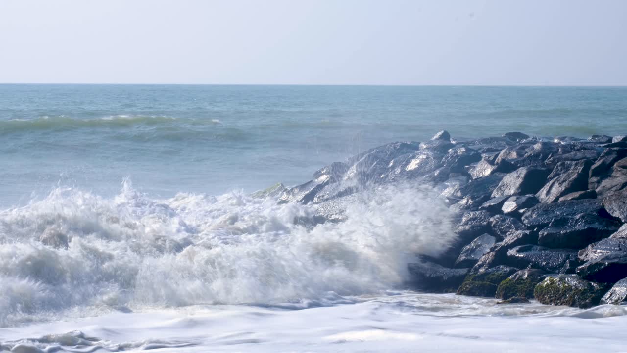 Slow motion big frothy whitewash waves crashing over rocky seawall in southern Sri Lanka