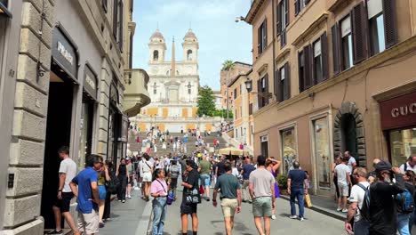 crowd of people walking by gucci and prada store to the famous spanish steps in rome, italy