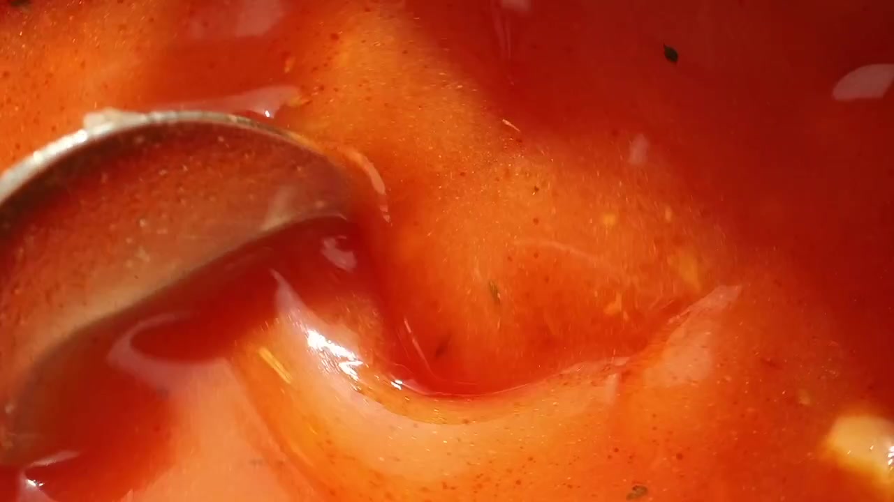 Primo piano di un cucchiaio che mescola zuppa di pomodoro rossa
