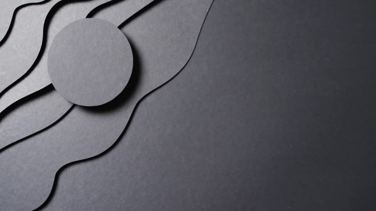 Video of close up of circle of black paper on waves cut out and copy space on black background