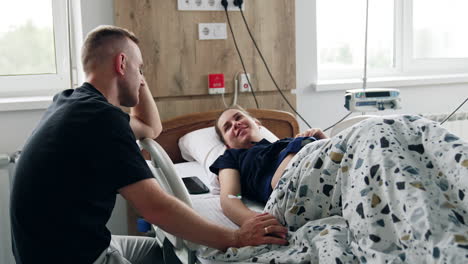 man is holding his pregnant wife's hand while she's tested on the medical equipment. diagnostics and fetal heart monitoring before the labor.