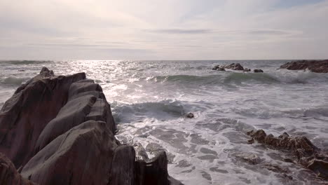 waves breaking against a rocky cove on a summer’s evening in slow motion