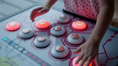 niña golpear los botones encendidos lo más rápido posible jugando en la máquina de arcade de frijoles traviesos