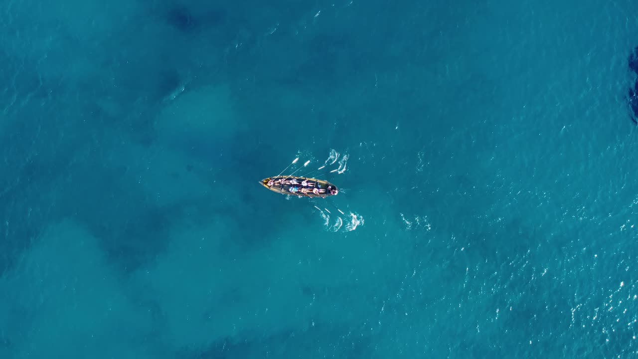 toma aérea siguiendo un bote y un equipo de remeros atléticos en el agua