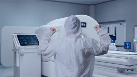 back view of asian male scientist celebrating the succeed while standing with mri machine in the hospital
