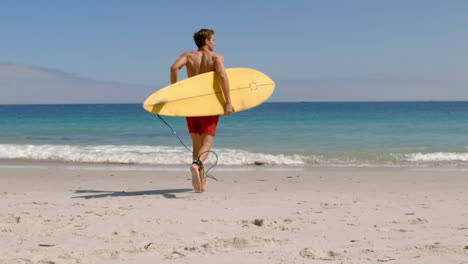 Schöner-Mann-Läuft-Mit-Surfbrett-Im-Wasser