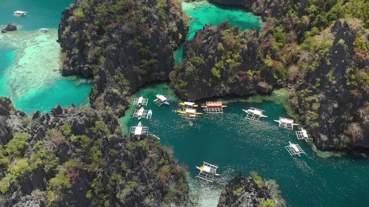 Toma aérea inclinada de dron de lagunas turquesas, acantilados de piedra caliza y barcos Paraw, en un día soleado en la isla de Coron, Filipinas, Asia