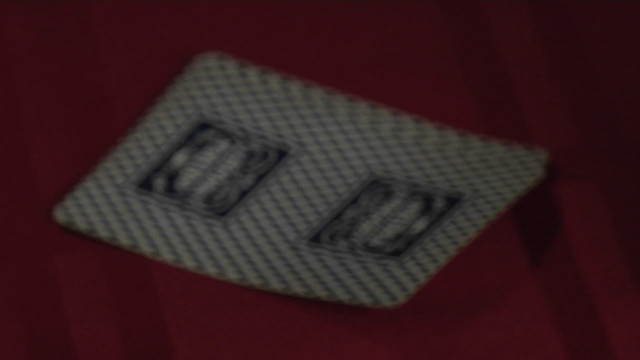 A hand turns up the corner of two playing cards to reveal a King and an Ace